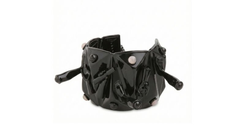 Three-quarter view of Milius COMPRESSION black varnished cuff / bracelet showing sculptural protrusions and polished stone details.