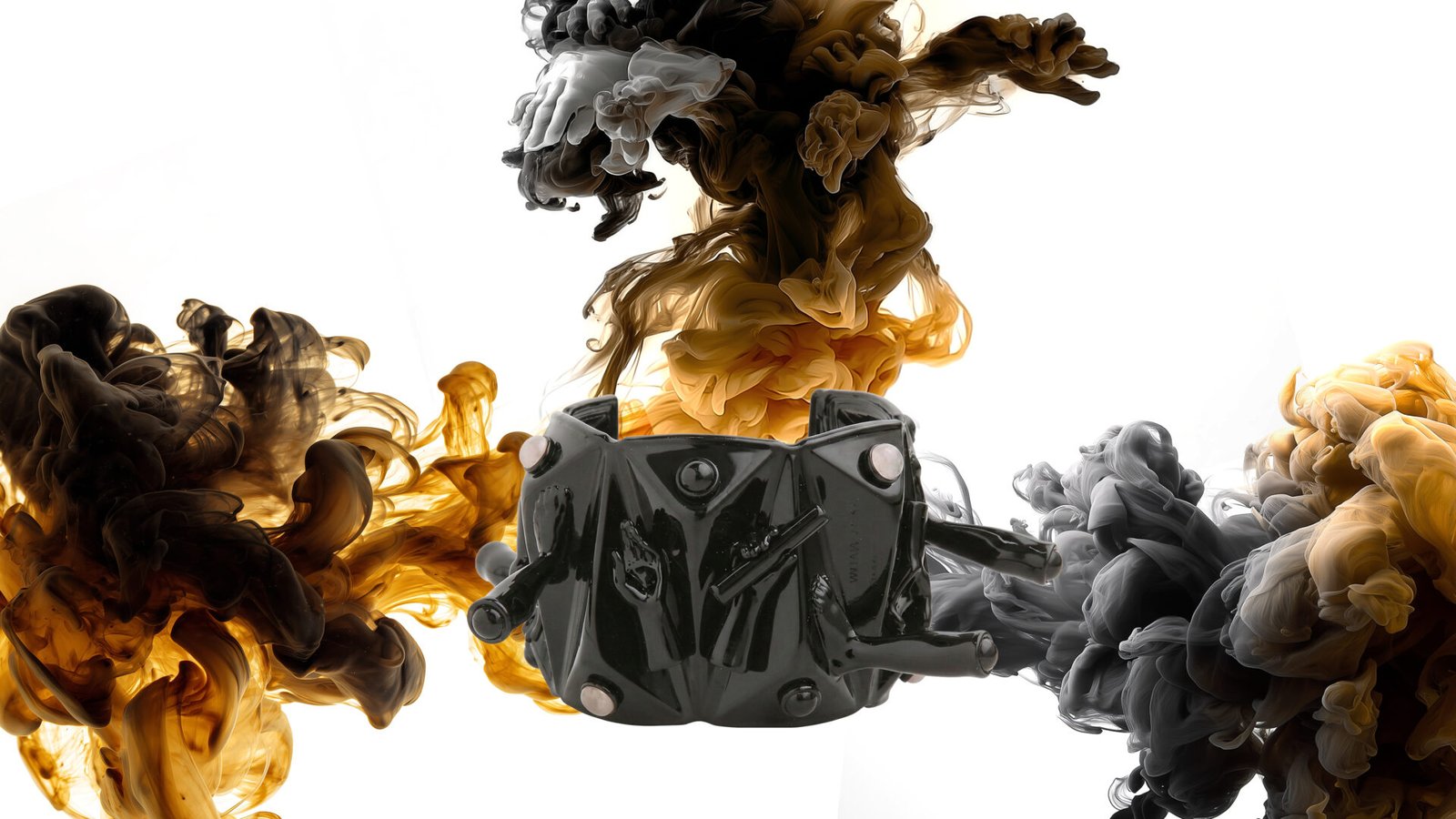 Milius - COMPRESSION -black varnished cuff / bracelet suspended within swirling black, amber, and white ink clouds on a white background.