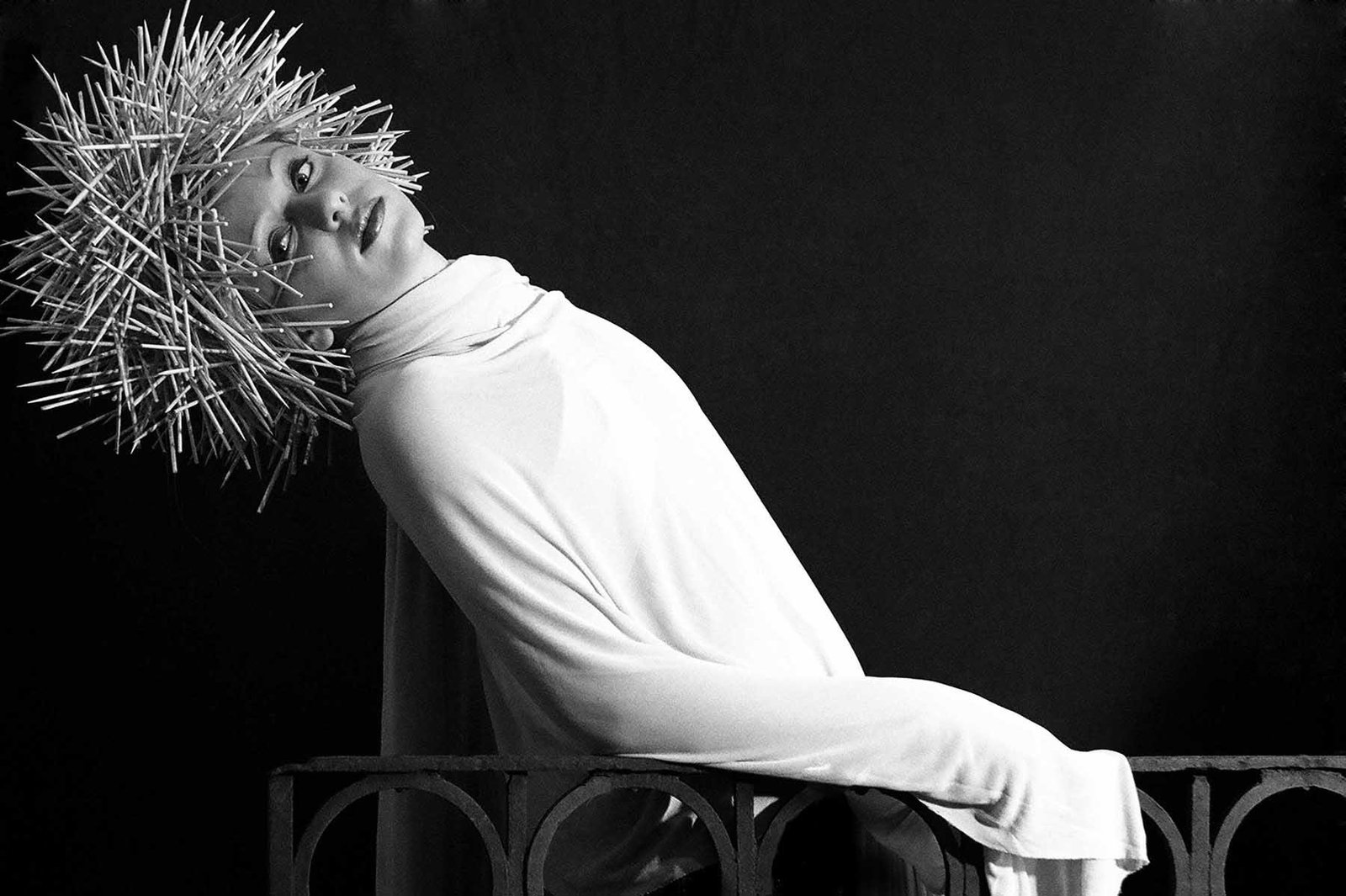Black-and-white portrait photograph by Milan Stamenovic depicting a figure draped in white fabric and wearing a sculptural spiked headpiece, exploring heightened visibility, isolation, and the erosion of authentic selfhood within contemporary portrait photography (2004–2005).