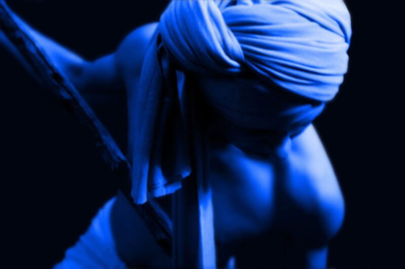 Mythic blue-toned fine art portrait of a human figure wrapped in cloth, illuminated by directional light, exploring memory, vulnerability, and embodied transformation in analog photography by Milan Stamenovic.