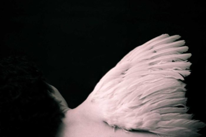 Fine art analog photograph showing a human back with a single wing attached, symbolising flight, loss, and human aspiration in a myth-inspired portrait by Milan Stamenovic.