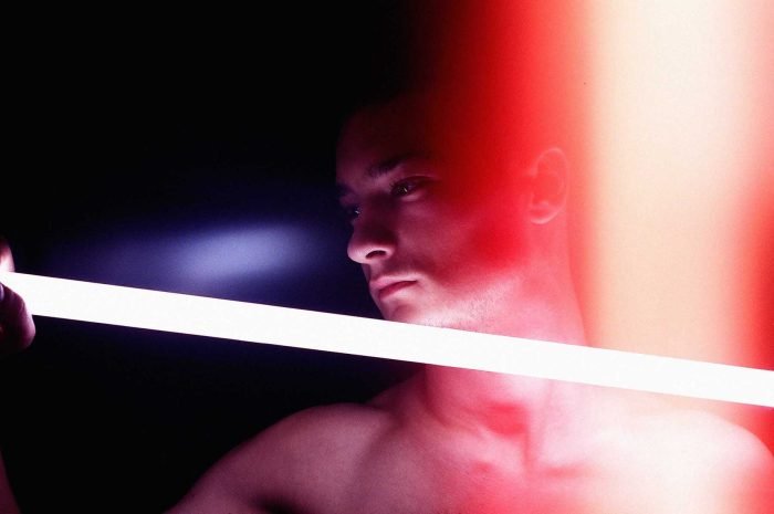 Contemporary portrait photograph exploring illumination as a volatile force, where light behaves like flame, carrying memory, heat, and consequence across the human face and body.