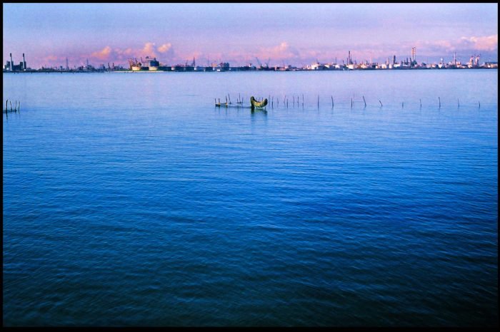 Open sea and distant industrial horizon photographed on analog film by Milan Stamenovic, exploring memory, human absence, and the sea as witness in Landscapes of the Remembering World.